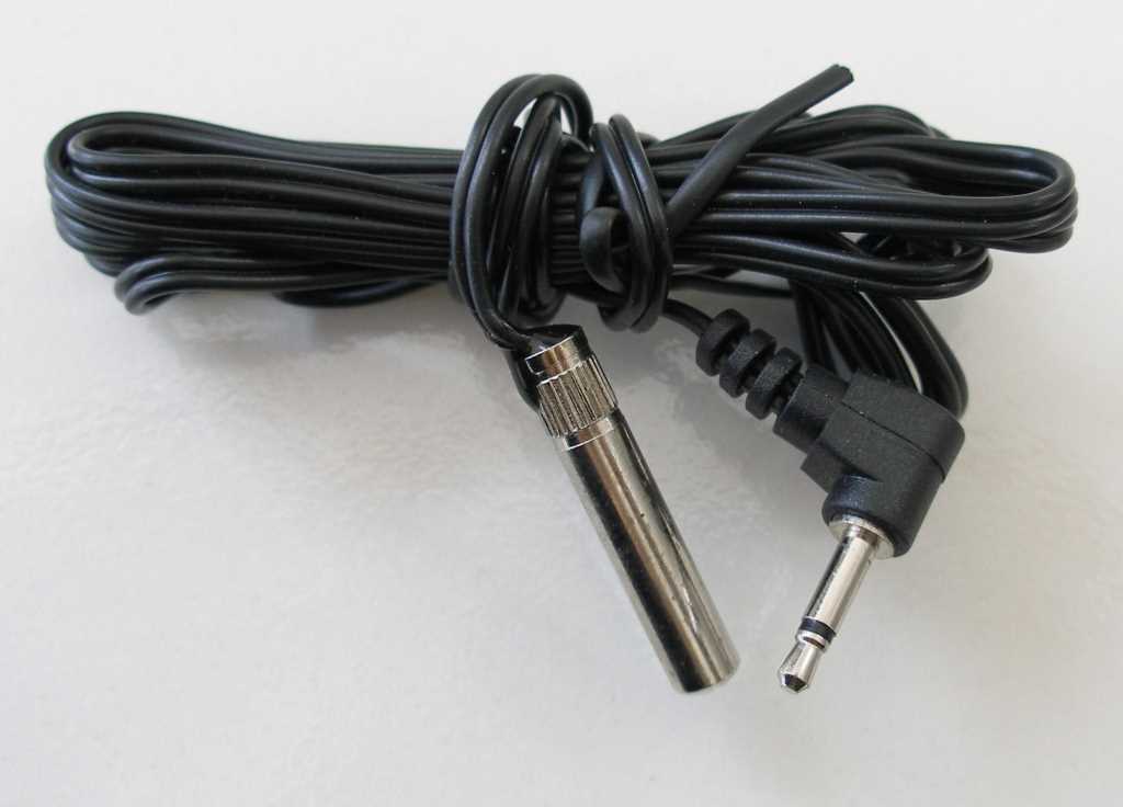 Aufgerolltes schwarzes Kabel mit Metallstecker und abgewinkeltem 3,5-mm-Klinkenstecker auf weißem Hintergrund