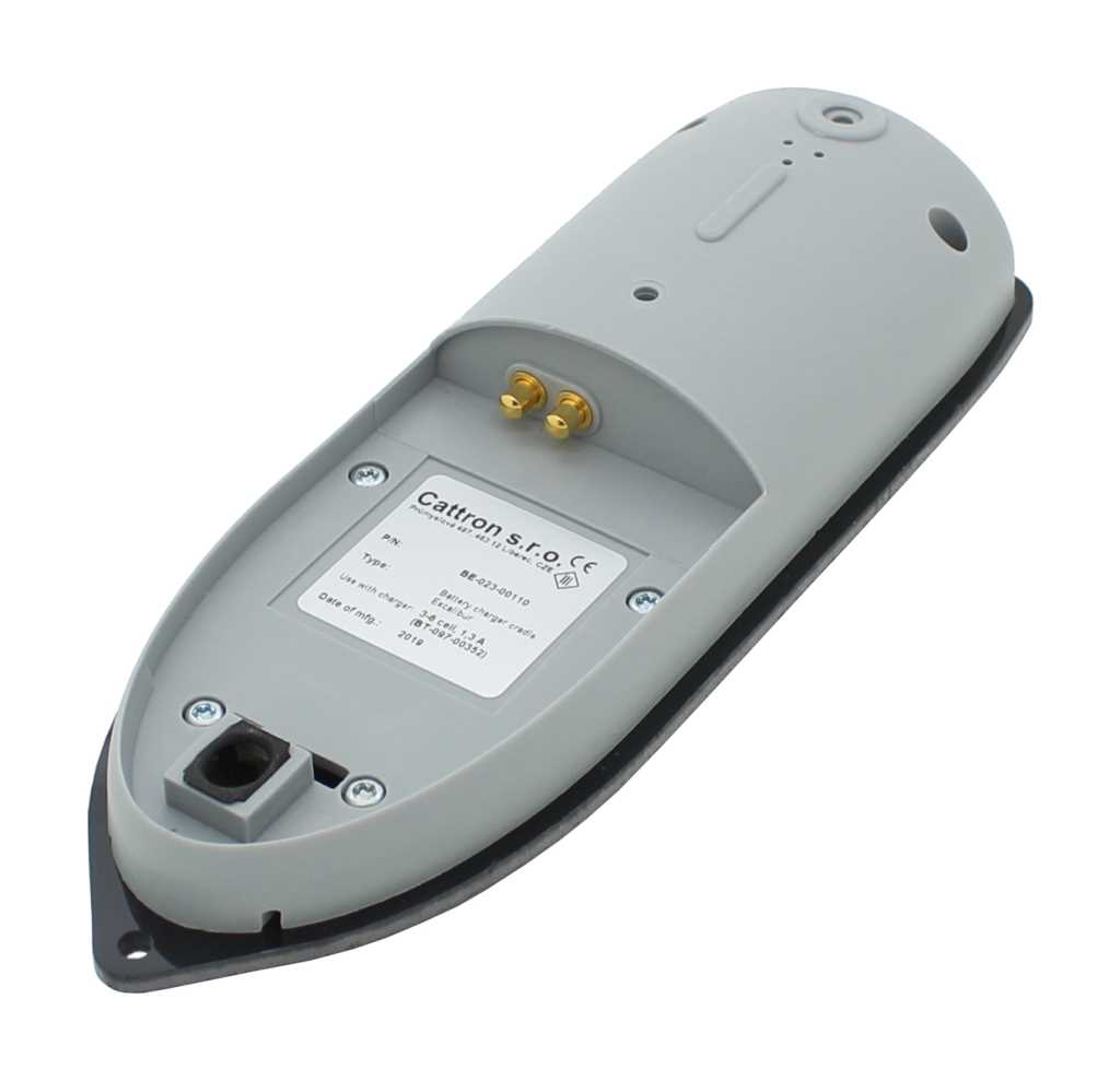 Graue Ladeschale mit zwei goldenen Kontaktstiften, Anschlussbuchse und Etikett, auf schwarzer Grundplatte schräg liegend